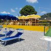 Spiaggia con ombrelloni blu e sdraio di fronte a un chiosco con sedie e tavoli.