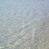 Acqua limpida che lambisce una spiaggia sabbiosa.
