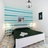 Camera con letto matrimoniale bianco, parete a righe blu e lampadari pendenti.