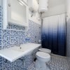 Bagno con motivi blu, doccia con tenda sfumata e specchio sopra il lavandino.