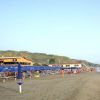 Spiaggia con ombrelloni blu, bagnanti sulla sabbia e mare.